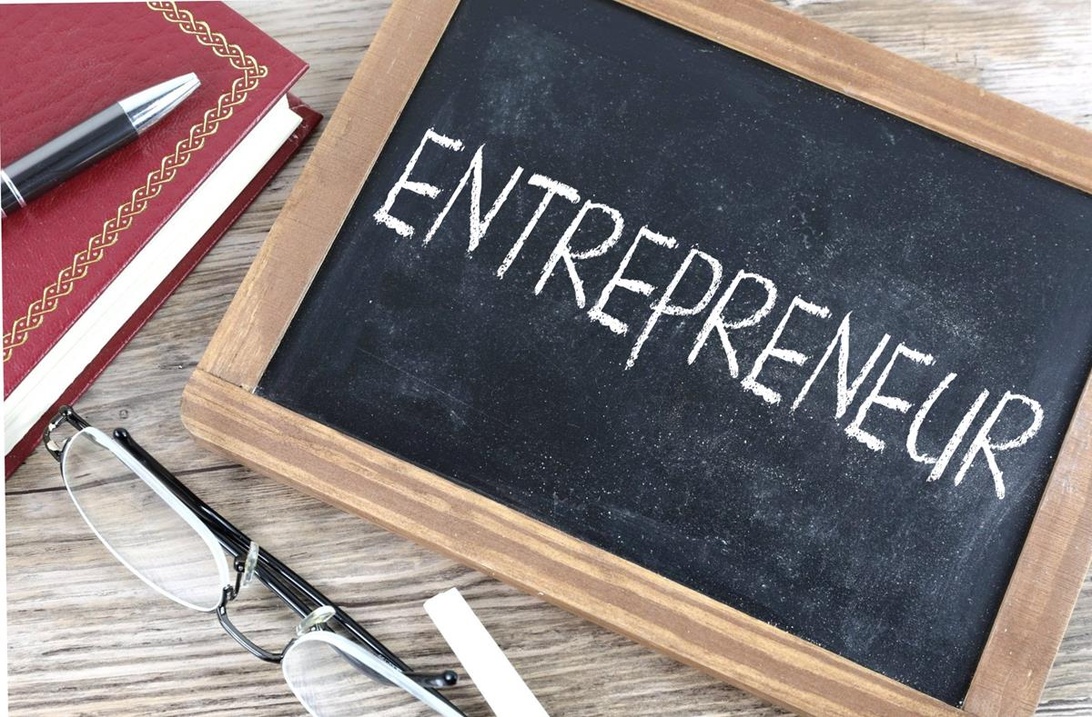 Skrivbord med en liten tavla där det står 'ENTREPRENEUR', vilket symboliserar starten på en företagsresa.